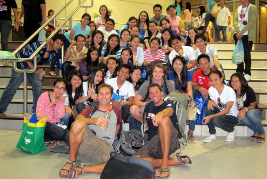 Visit50 founder Todd with other backpacker traveler friends and a group of Filipino kids in Cebu. Taking photos with strangers, a local Philippines travel experience